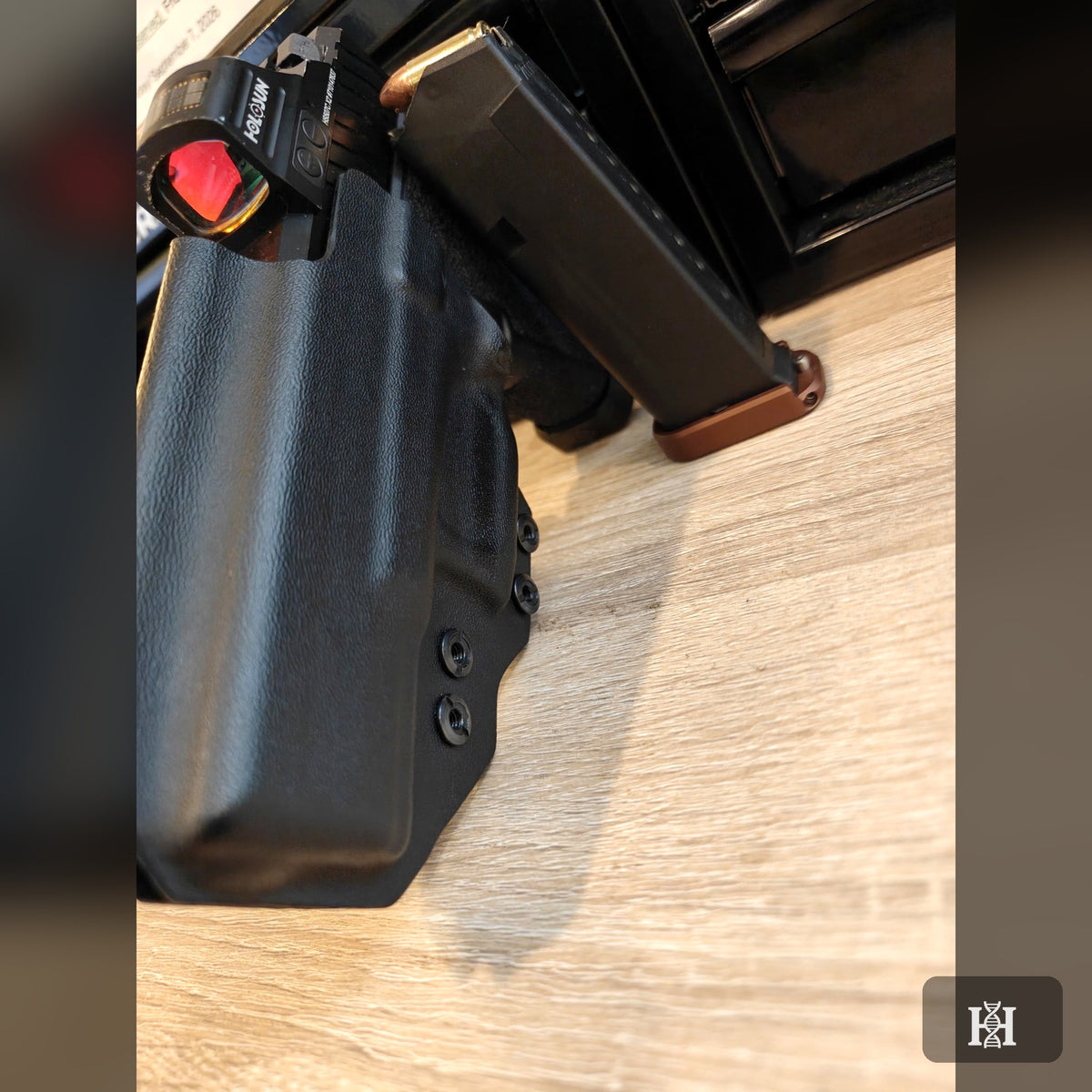 Black AIWB holster with Holosun pistol beside spare magazine